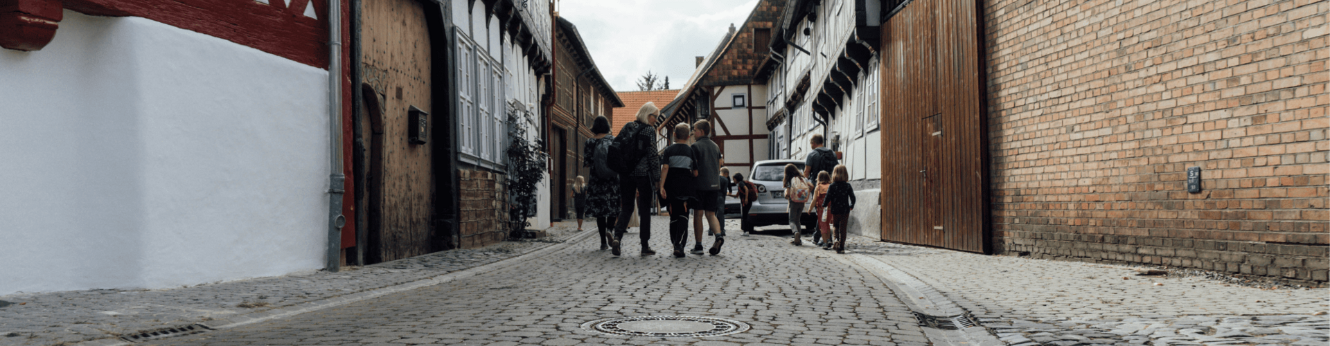Gruppe von Erwachsenen und Kindern unterwegs in einer altertümlichen Straße