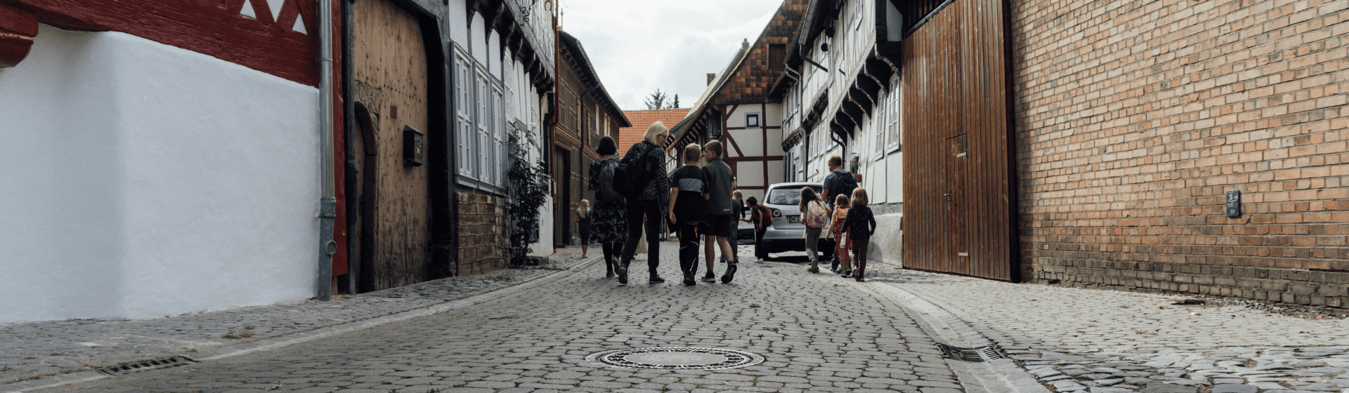 Gruppe von Erwachsenen und Kindern unterwegs in einer altertümlichen Straße