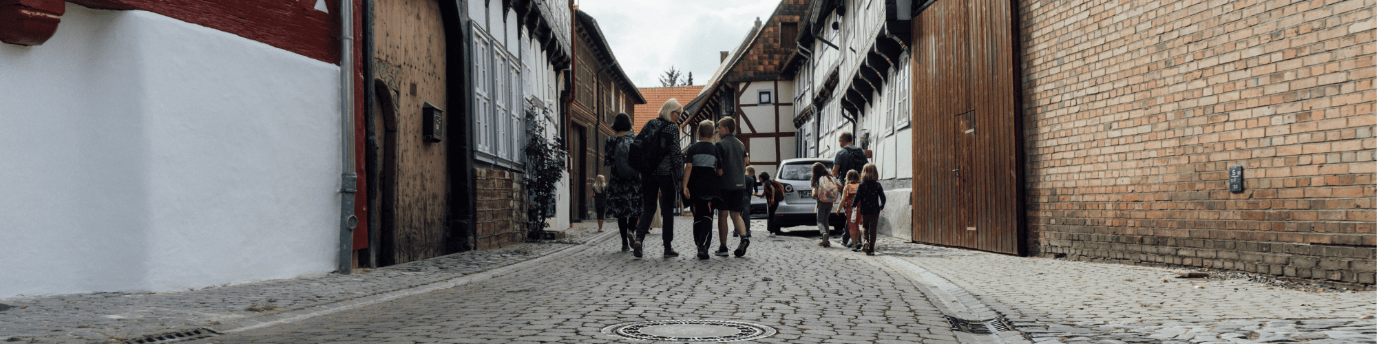 Gruppe von Erwachsenen und Kindern unterwegs in einer altertümlichen Straße